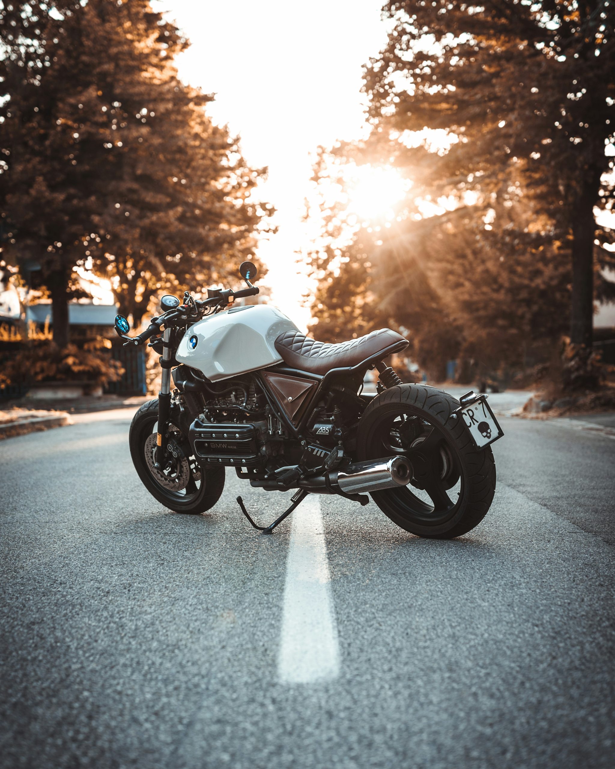 A motorcycle parked in the middle of a shady street.